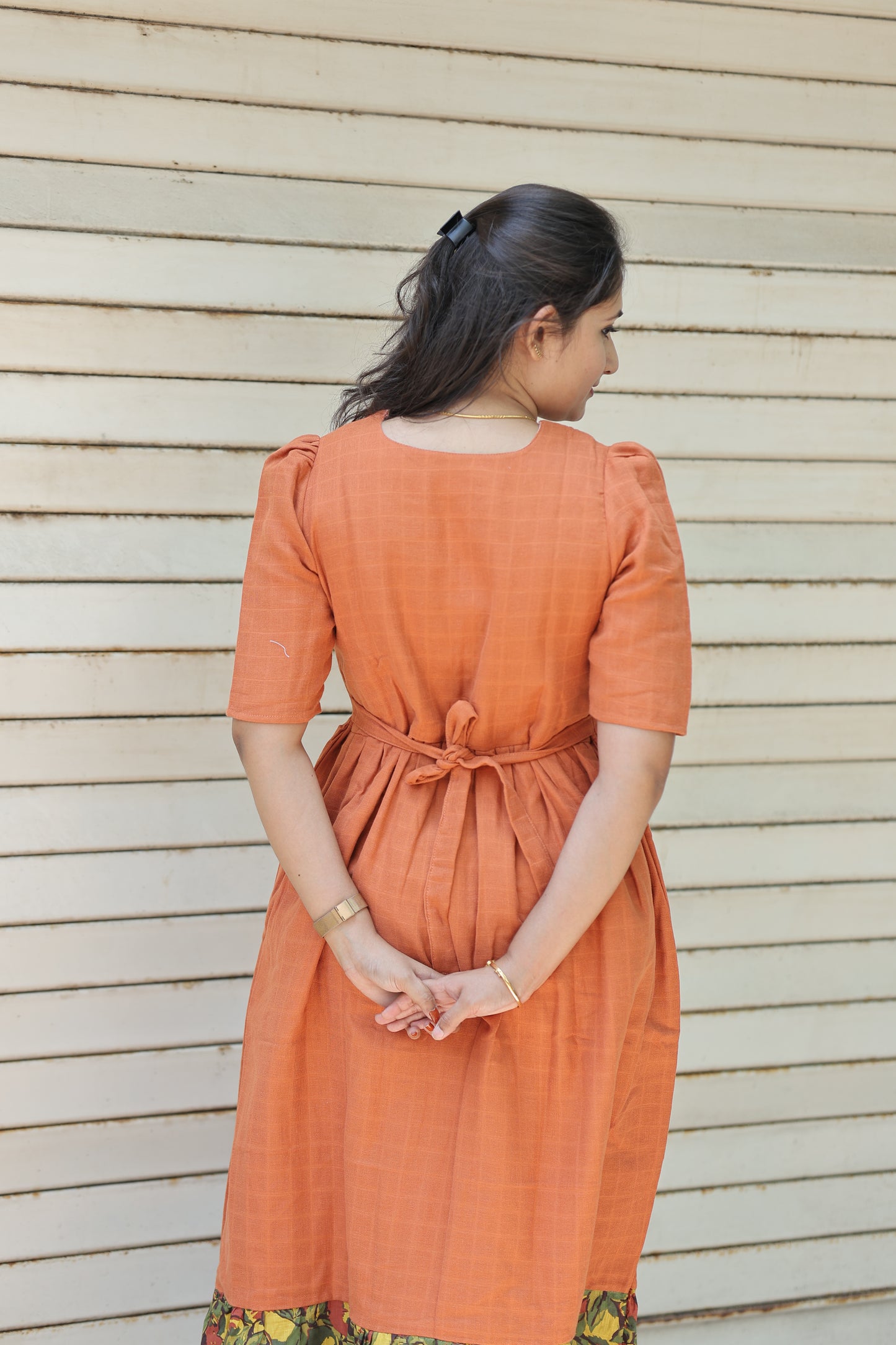 Back view of neemai's orange muslin cotton maternity and feeding dress with adjustable back tie, airy breathable fabric and comfortable summer friendly fit, plus size muslin dress.