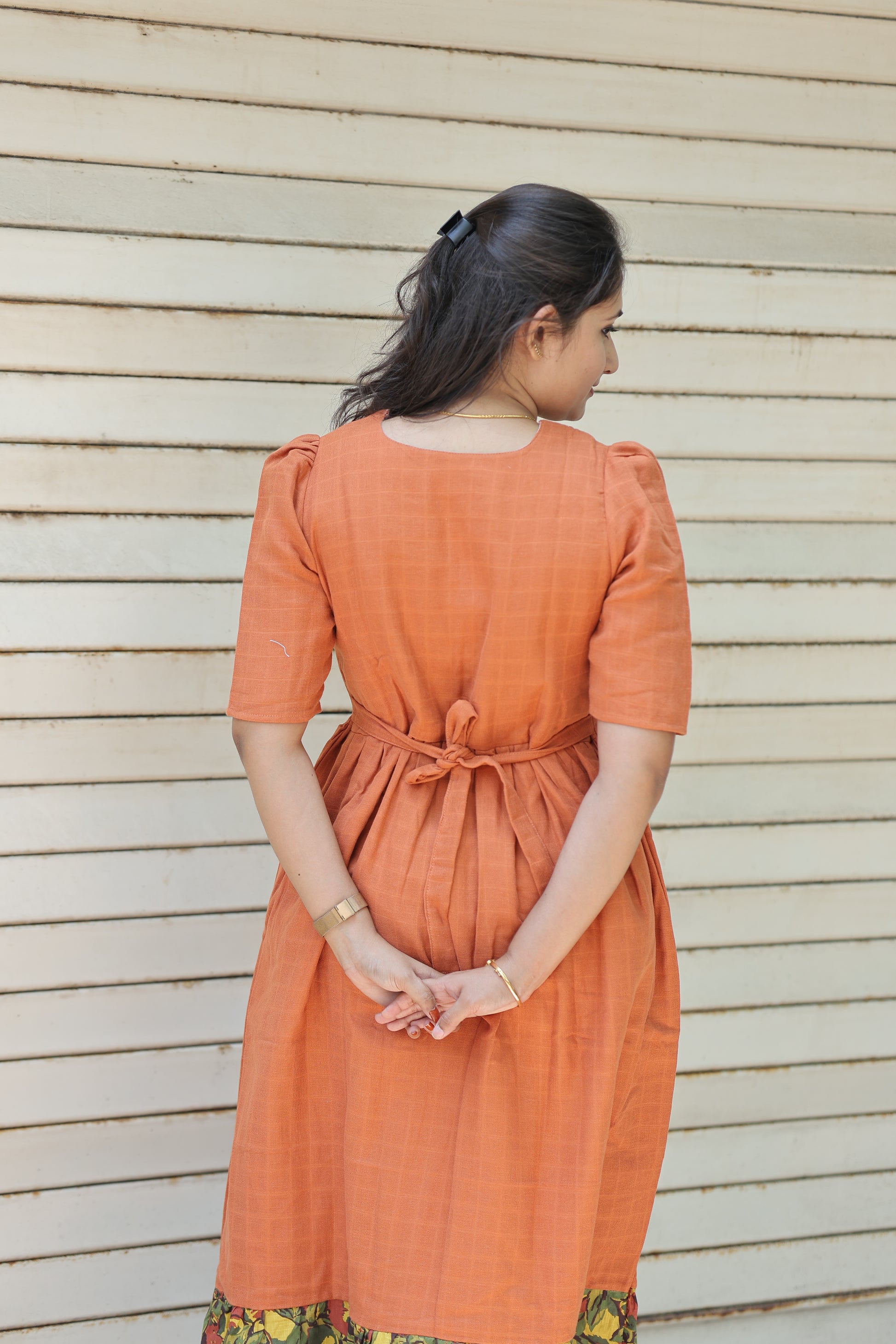 Back view of neemai's orange muslin cotton maternity and feeding dress with adjustable back tie, airy breathable fabric and comfortable summer friendly fit, plus size muslin dress.